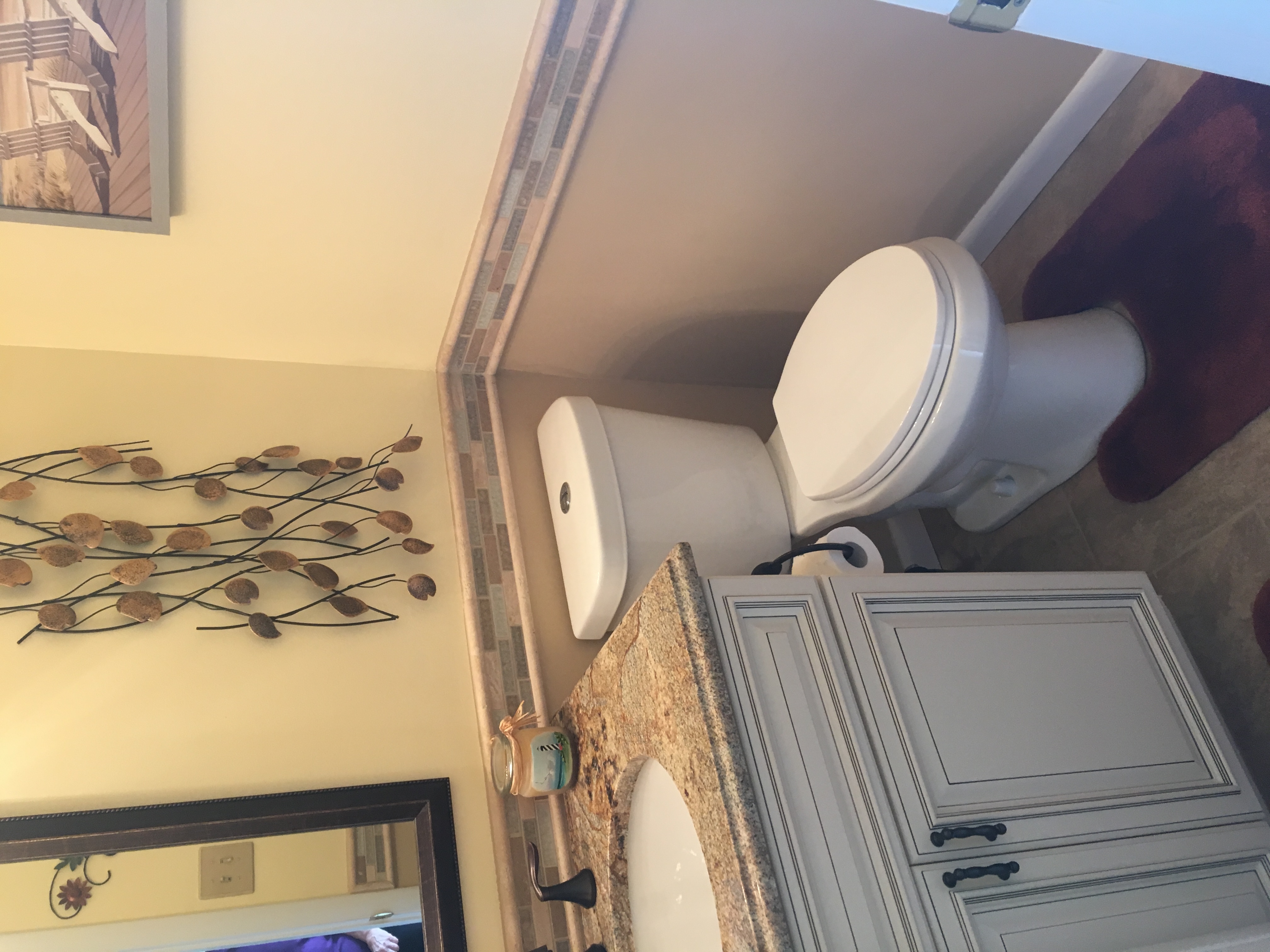 Small bathroom remodel featuring a cream vanity with granite countertop, decorative wall tile border, and warm neutral tones for a cozy powder room design.
